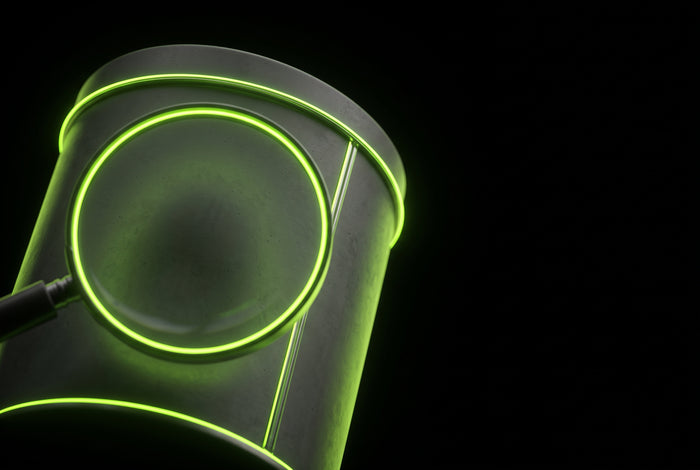 Magnifying lens over a pouch tin outlined in green neon - reading a caffeine label